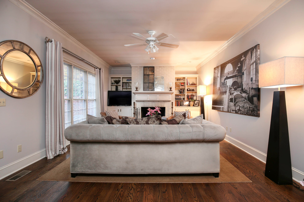 Kleines, Abgetrenntes Klassisches Wohnzimmer mit grauer Wandfarbe, dunklem Holzboden, Kamin, Kaminumrandung aus Backstein, Eck-TV und braunem Boden in Sonstige