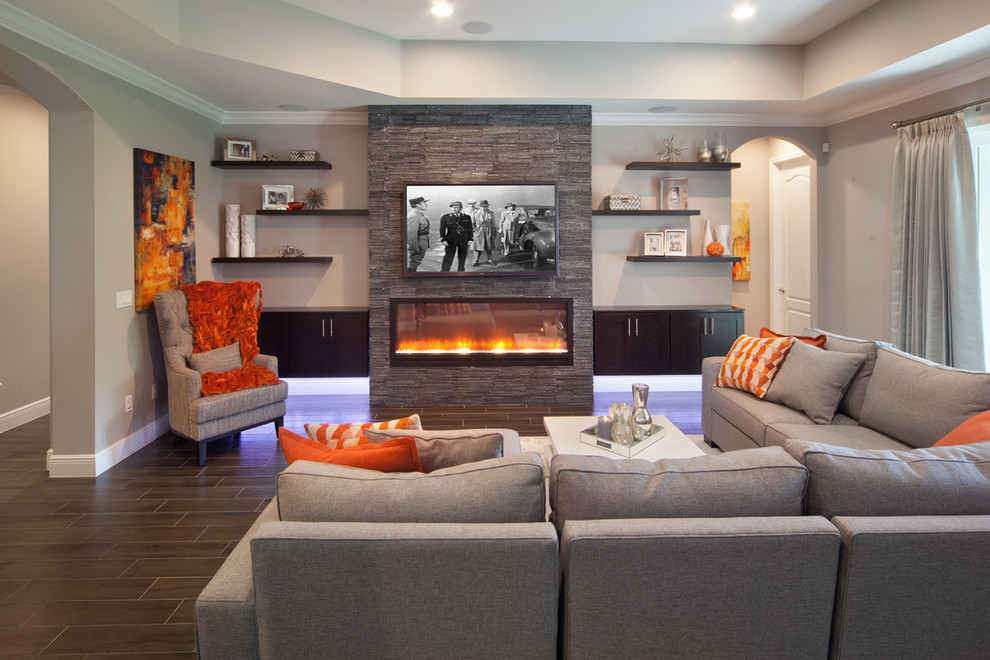 Family room - large transitional enclosed porcelain tile family room idea in Orlando with gray walls, a ribbon fireplace, a stone fireplace and a wall-mounted tv