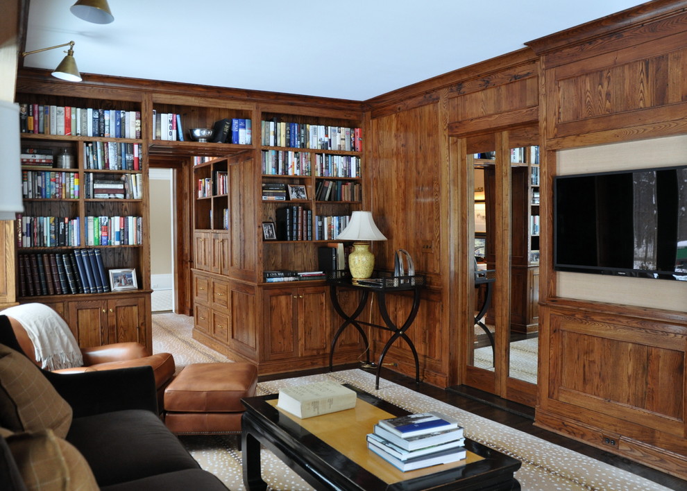 Cette photo montre une salle de séjour craftsman de taille moyenne et fermée avec une bibliothèque ou un coin lecture, un mur beige, parquet foncé, aucune cheminée et un téléviseur fixé au mur.