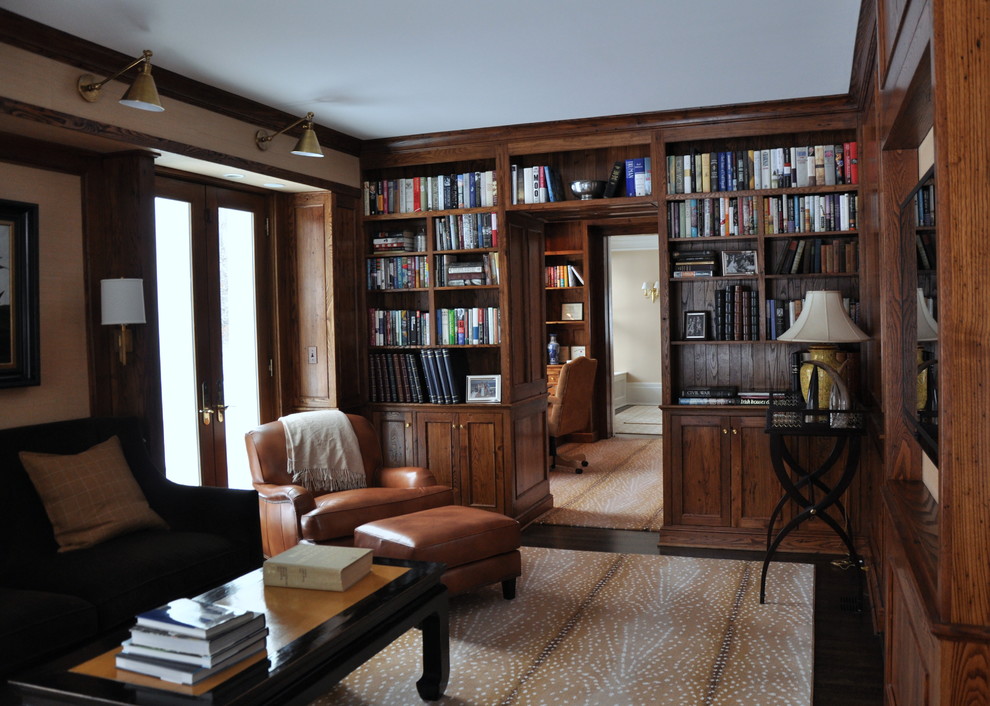 Ejemplo de sala de estar con biblioteca cerrada de estilo americano de tamaño medio sin chimenea con suelo de madera oscura, televisor colgado en la pared y paredes beige