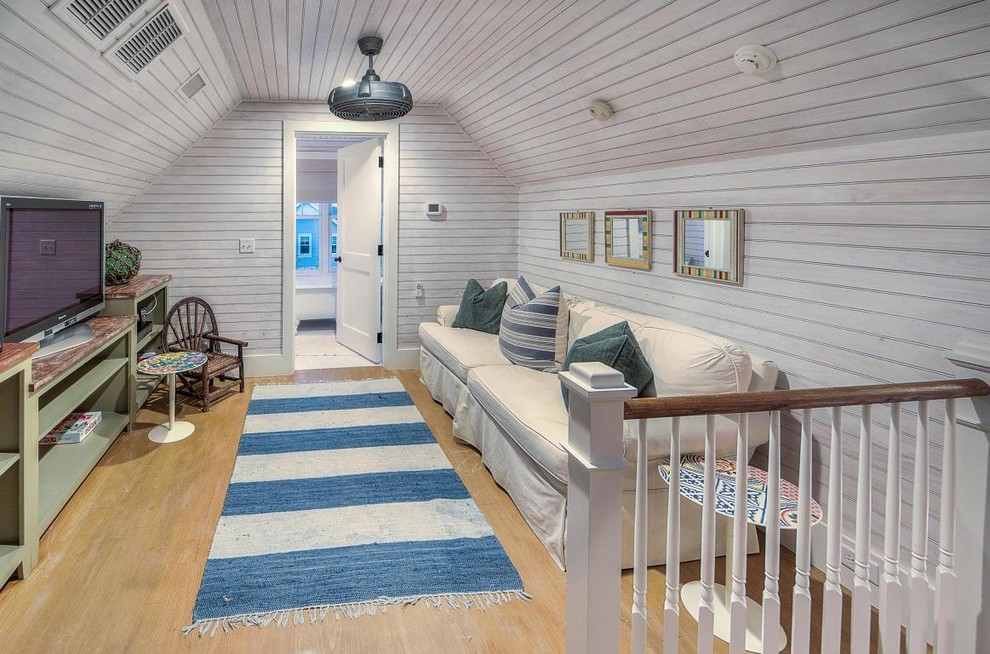 Imagen de sala de juegos en casa marinera pequeña con paredes blancas, suelo de madera clara y televisor independiente