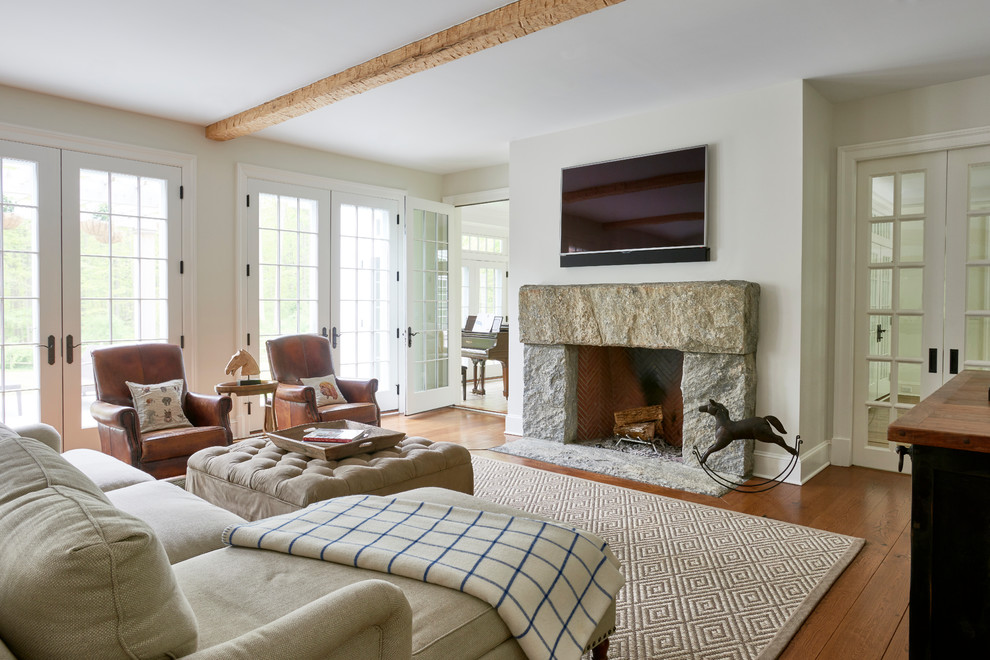 Foto di un soggiorno classico di medie dimensioni e aperto con pavimento in legno massello medio, cornice del camino in pietra, TV a parete e pavimento marrone