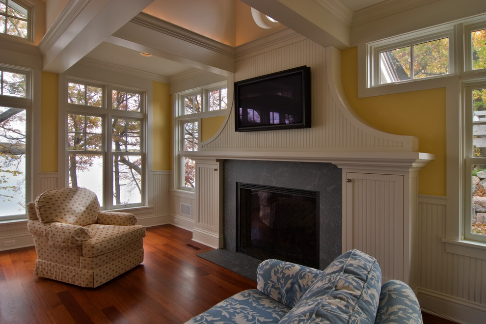 Идея дизайна: открытая гостиная комната среднего размера в классическом стиле с желтыми стенами, паркетным полом среднего тона, стандартным камином, фасадом камина из камня и телевизором на стене