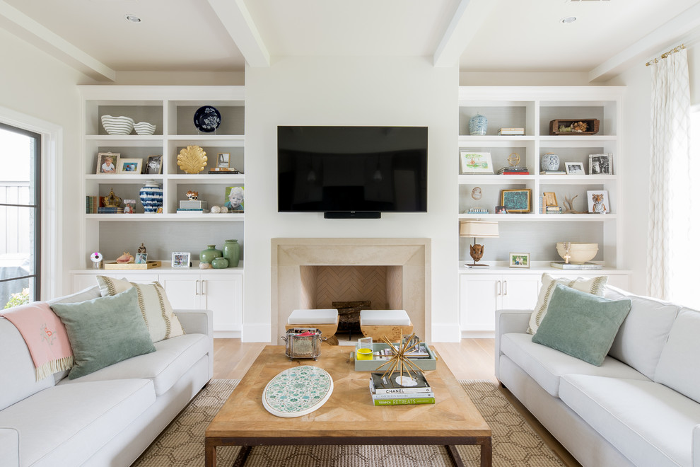 Diseño de sala de estar tradicional renovada con paredes blancas, suelo de madera clara, todas las chimeneas, marco de chimenea de piedra y televisor colgado en la pared