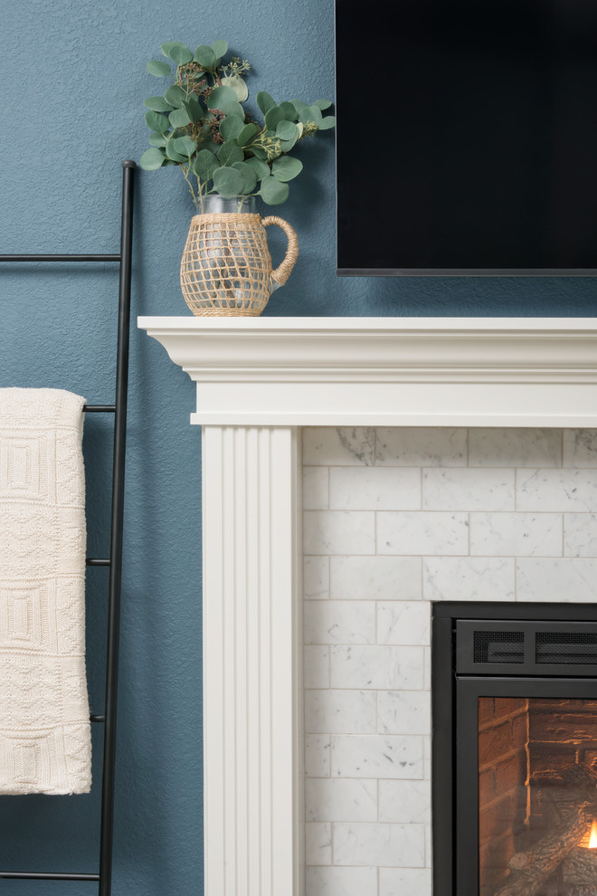 Idée de décoration pour une salle de séjour tradition de taille moyenne avec un mur bleu, parquet foncé, une cheminée standard, un manteau de cheminée en pierre, un téléviseur fixé au mur et un sol marron.