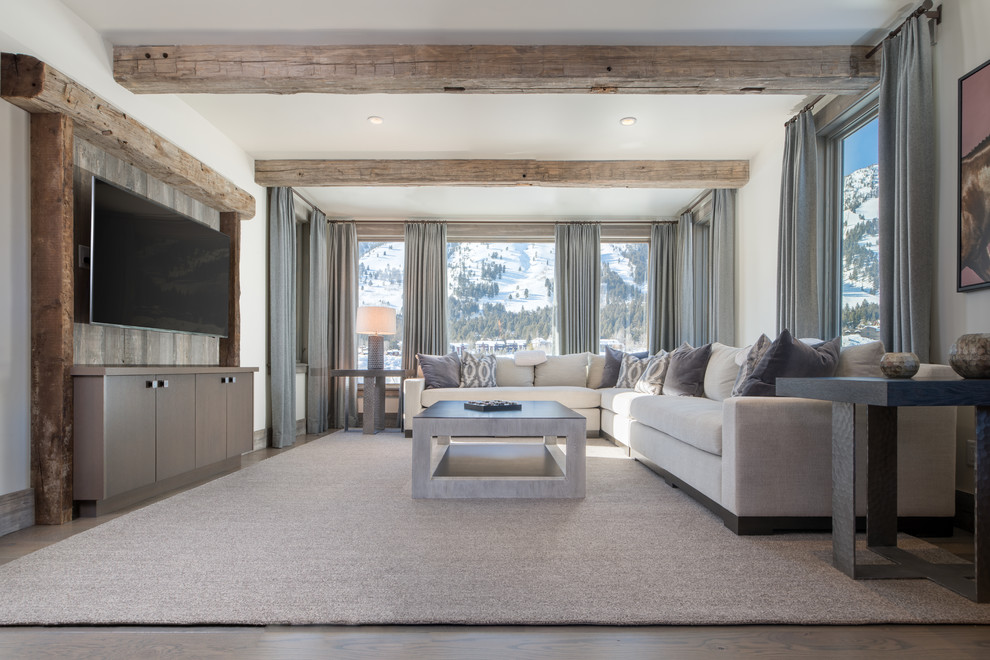Modelo de sala de estar rural con paredes blancas, suelo de madera oscura, televisor colgado en la pared y suelo marrón