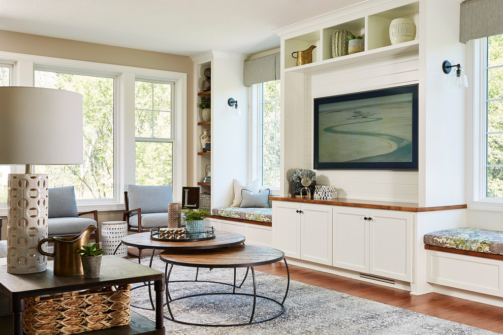Imagen de sala de estar costera sin chimenea con paredes beige, suelo de madera en tonos medios, pared multimedia y alfombra