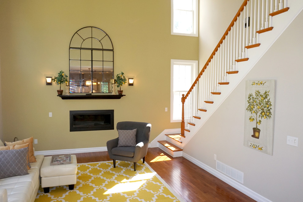 Cette photo montre une grande salle de séjour tendance fermée avec un mur jaune, parquet foncé, cheminée suspendue, un manteau de cheminée en métal, aucun téléviseur et un sol marron.