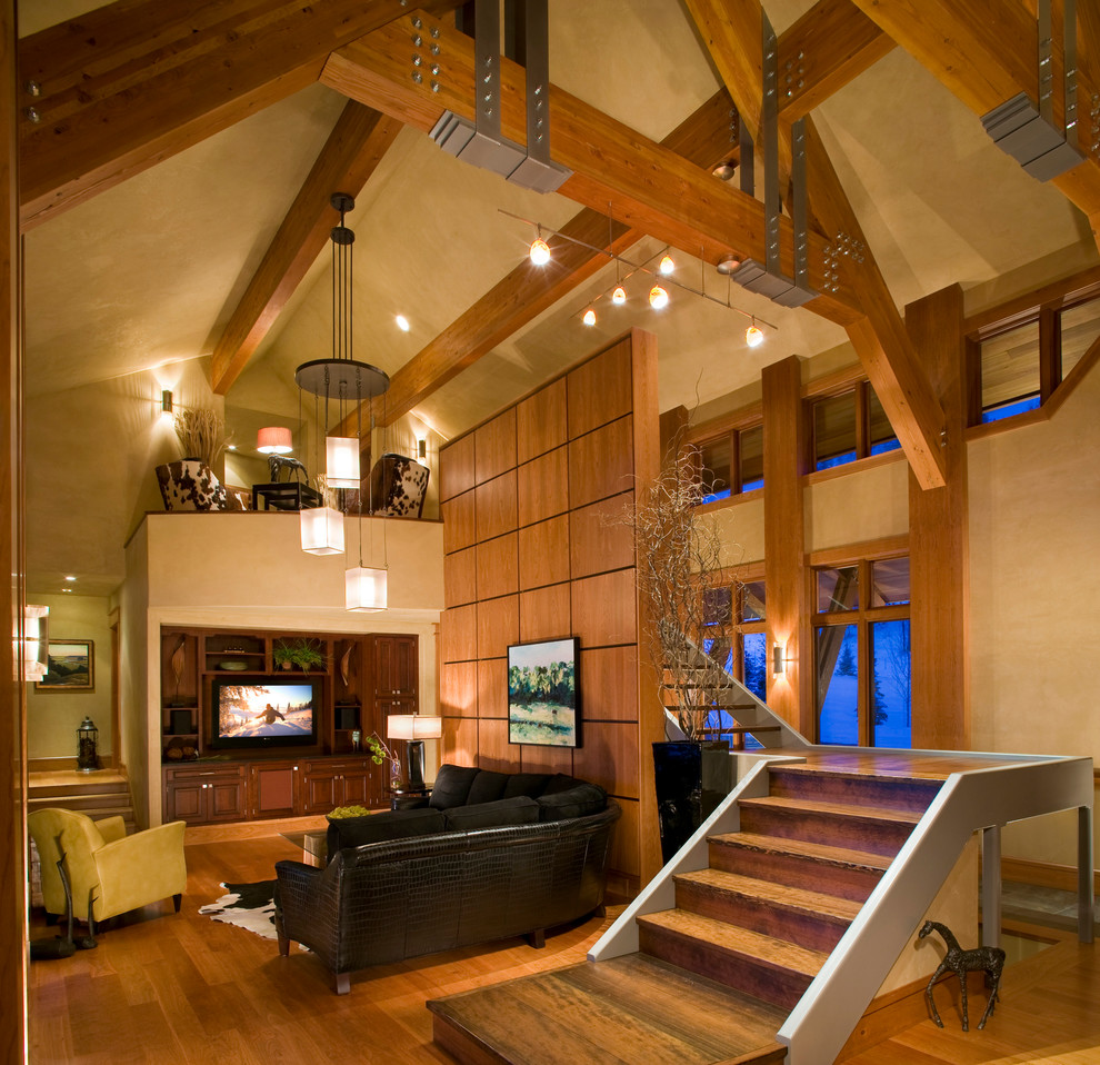 Diseño de sala de estar abierta rústica grande sin chimenea con paredes beige, suelo de madera clara, pared multimedia y suelo marrón