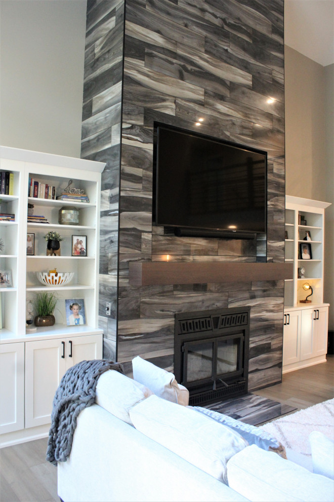 Exempel på ett mycket stort allrum med öppen planlösning, med grå väggar, mellanmörkt trägolv, en standard öppen spis, en spiselkrans i trä, en väggmonterad TV och grått golv