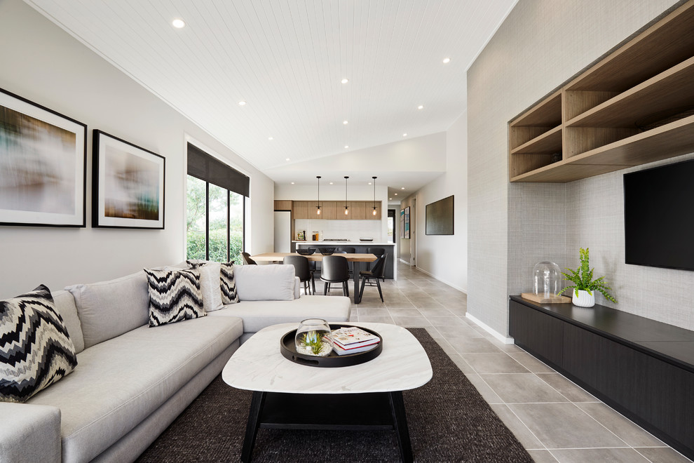 Стильный дизайн: открытая гостиная комната среднего размера в современном стиле с телевизором на стене, серыми стенами и серым полом - последний тренд