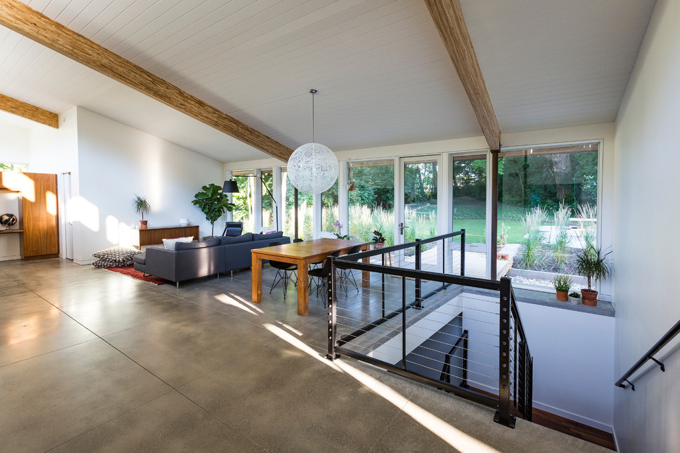 Immagine di un soggiorno design aperto con pareti bianche, pavimento in cemento e nessun camino