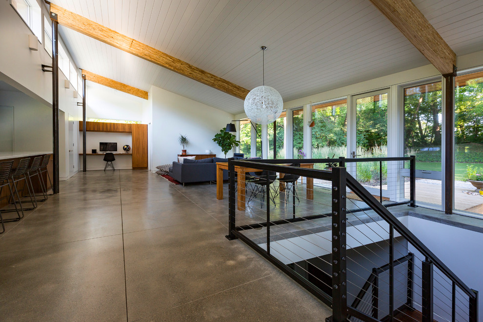 Cette image montre une salle de séjour design ouverte avec un mur blanc, sol en béton ciré et aucune cheminée.