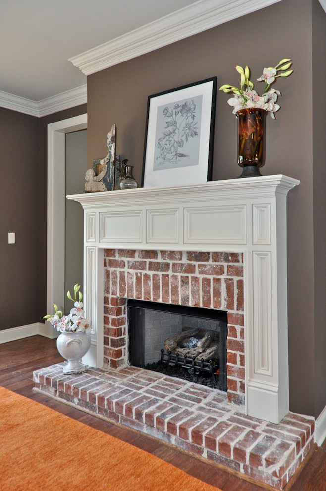 Idée de décoration pour une salle de séjour tradition avec un mur gris, parquet foncé, une cheminée standard, un manteau de cheminée en brique et un sol marron.