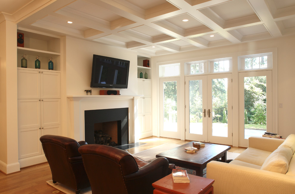 This is an example of a medium sized traditional open plan games room in Portland with white walls, medium hardwood flooring, a standard fireplace, a plastered fireplace surround and a wall mounted tv.