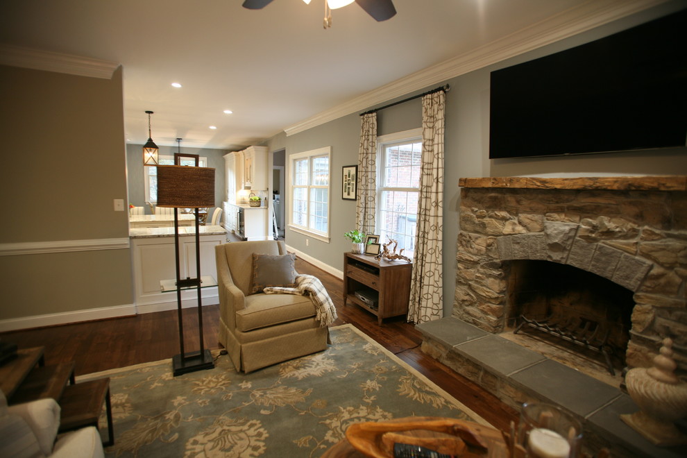 Réalisation d'une petite salle de séjour champêtre ouverte avec un mur bleu, un sol en bois brun, une cheminée standard, un manteau de cheminée en pierre, un téléviseur fixé au mur et un sol marron.