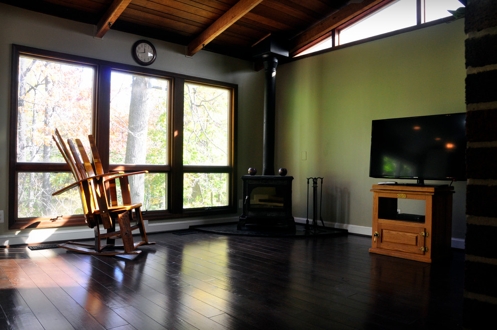 Cette image montre une salle de séjour traditionnelle de taille moyenne et ouverte avec un mur vert, parquet foncé, une cheminée d'angle, un manteau de cheminée en pierre et un téléviseur indépendant.