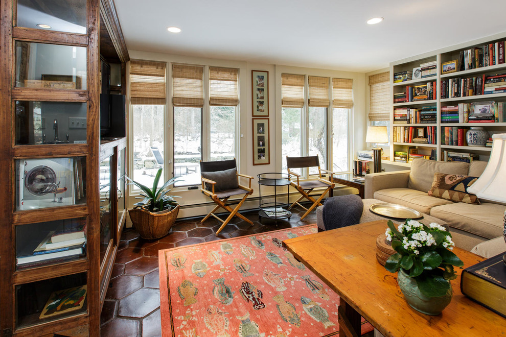 Diseño de sala de estar con biblioteca campestre pequeña con paredes amarillas y suelo de baldosas de terracota