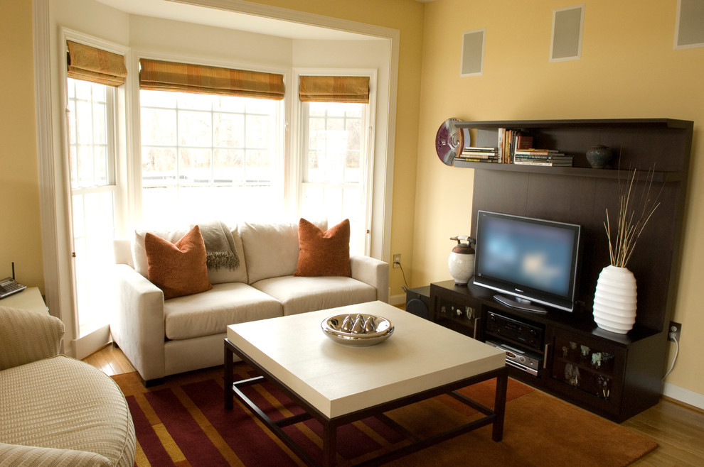 Ejemplo de sala de estar abierta actual pequeña con televisor independiente, paredes amarillas y suelo de madera en tonos medios