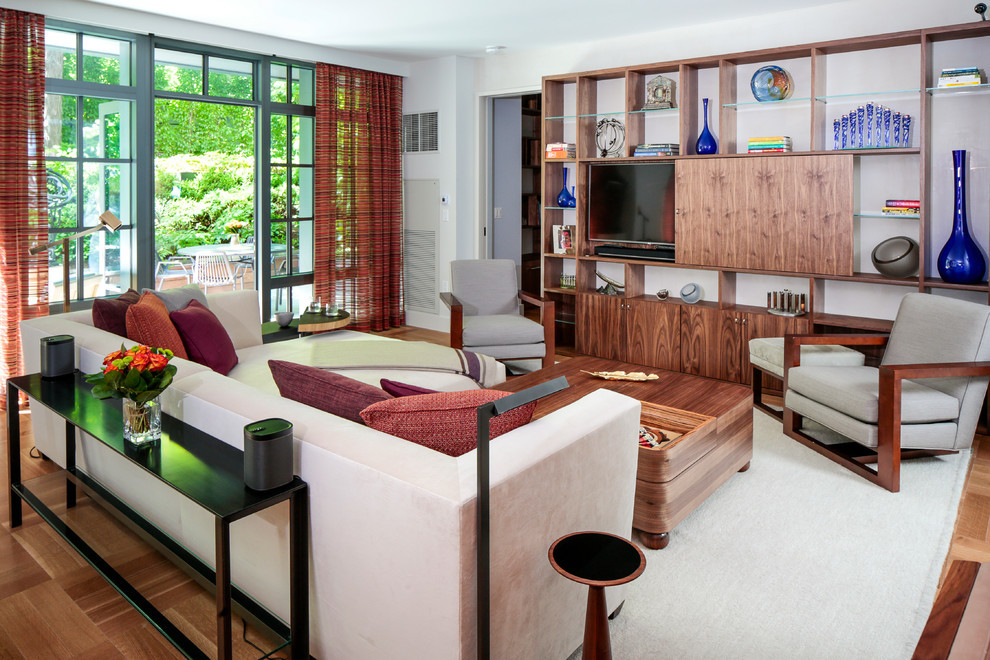 Ejemplo de sala de estar con biblioteca abierta actual grande sin chimenea con paredes blancas, suelo de madera clara y pared multimedia