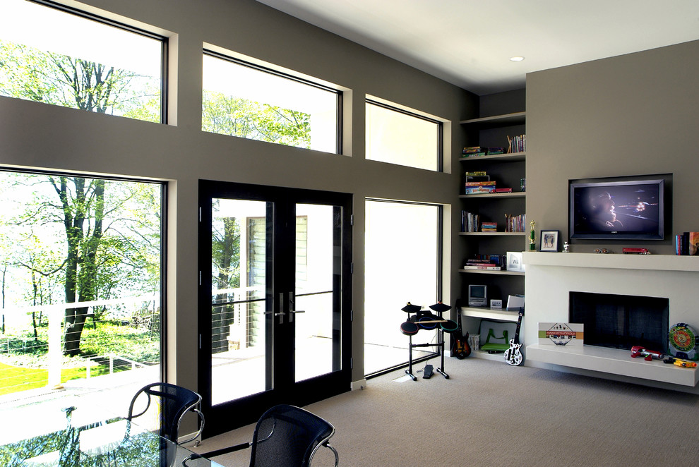 Large contemporary enclosed games room in Grand Rapids with grey walls, carpet, a standard fireplace, a stone fireplace surround, a game room, a wall mounted tv and grey floors.