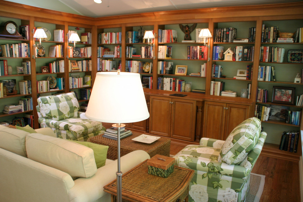 Cette image montre une salle de séjour traditionnelle de taille moyenne avec une bibliothèque ou un coin lecture, un mur vert, un sol en bois brun et aucune cheminée.