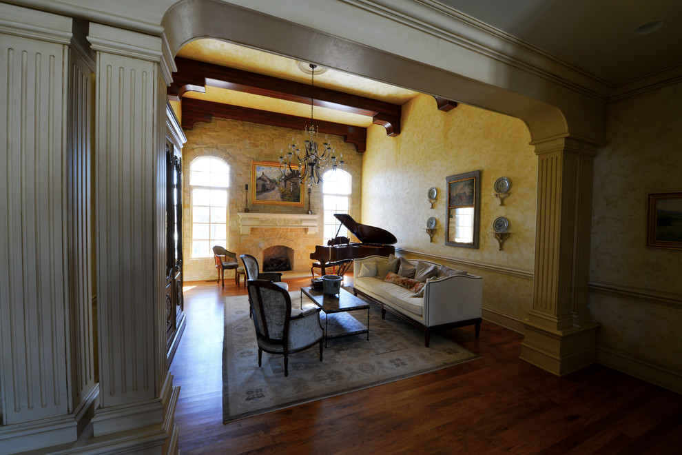 Cette image montre une grande salle de séjour traditionnelle ouverte avec un sol en bois brun, une cheminée standard, un manteau de cheminée en pierre, aucun téléviseur, une salle de musique, un mur multicolore et un sol marron.