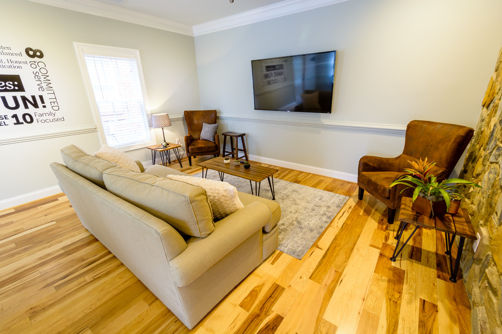 Diseño de sala de estar abierta de estilo de casa de campo de tamaño medio sin chimenea con paredes grises, suelo de madera en tonos medios, televisor colgado en la pared y suelo marrón