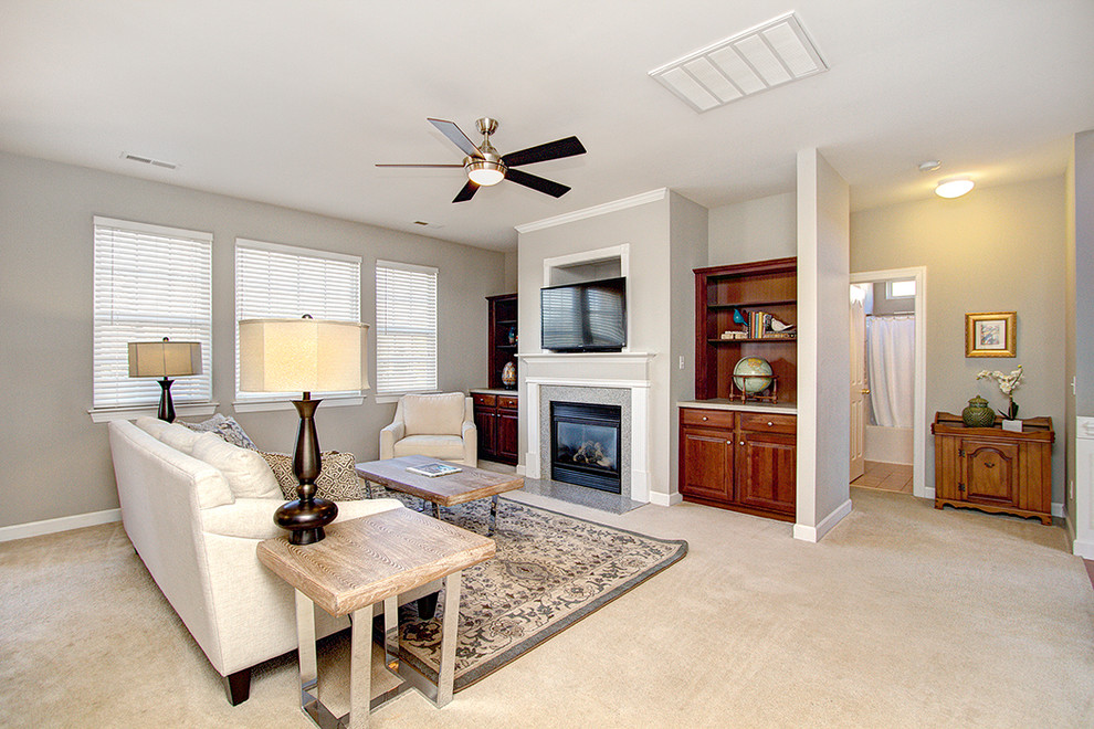 Cette image montre une salle de séjour traditionnelle ouverte avec un mur gris, une cheminée standard et un téléviseur encastré.