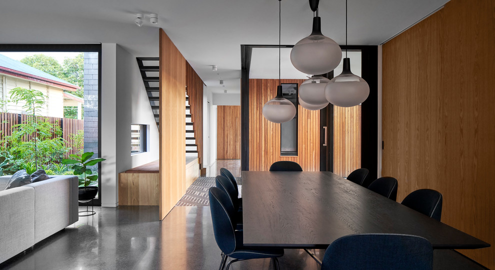 Modernes Esszimmer mit Betonboden, Eckkamin, Kaminumrandung aus Beton und schwarzem Boden in Melbourne