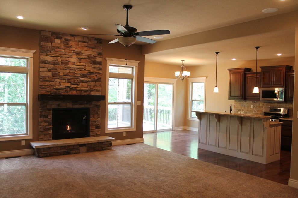 Elegant carpeted family room photo in Kansas City with beige walls, a standard fireplace and a stone fireplace