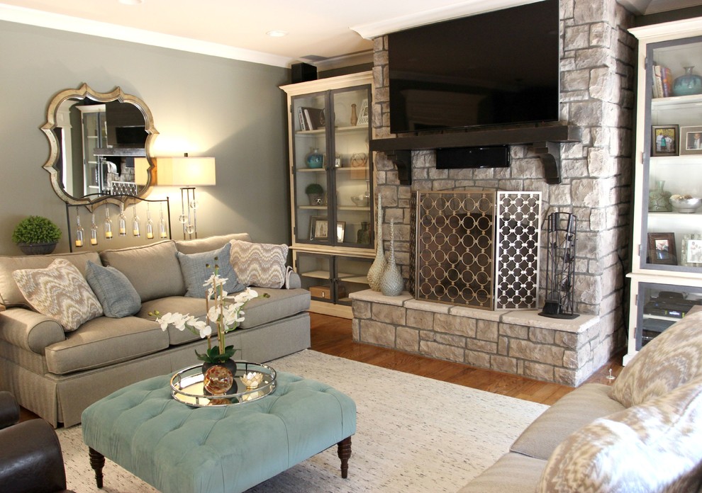 Aménagement d'une salle de séjour classique de taille moyenne et fermée avec un mur gris, un sol en bois brun, une cheminée standard, un manteau de cheminée en pierre, un téléviseur indépendant et un sol marron.
