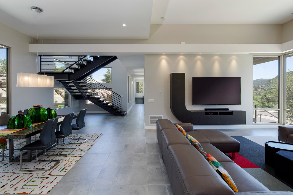 Immagine di un grande soggiorno design aperto con pareti grigie, pavimento in gres porcellanato, nessun camino, TV a parete e pavimento grigio