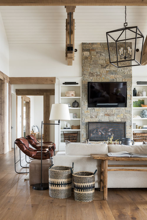This is an example of a large classic open plan games room in Salt Lake City with white walls, medium hardwood flooring, a two-sided fireplace, a stone fireplace surround, a wall mounted tv and brown floors.