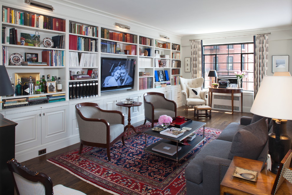 Imagen de sala de estar con biblioteca clásica con paredes blancas, suelo de madera oscura y pared multimedia