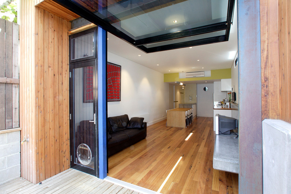 Cette image montre une salle de séjour design ouverte avec un mur blanc et un sol en bois brun.