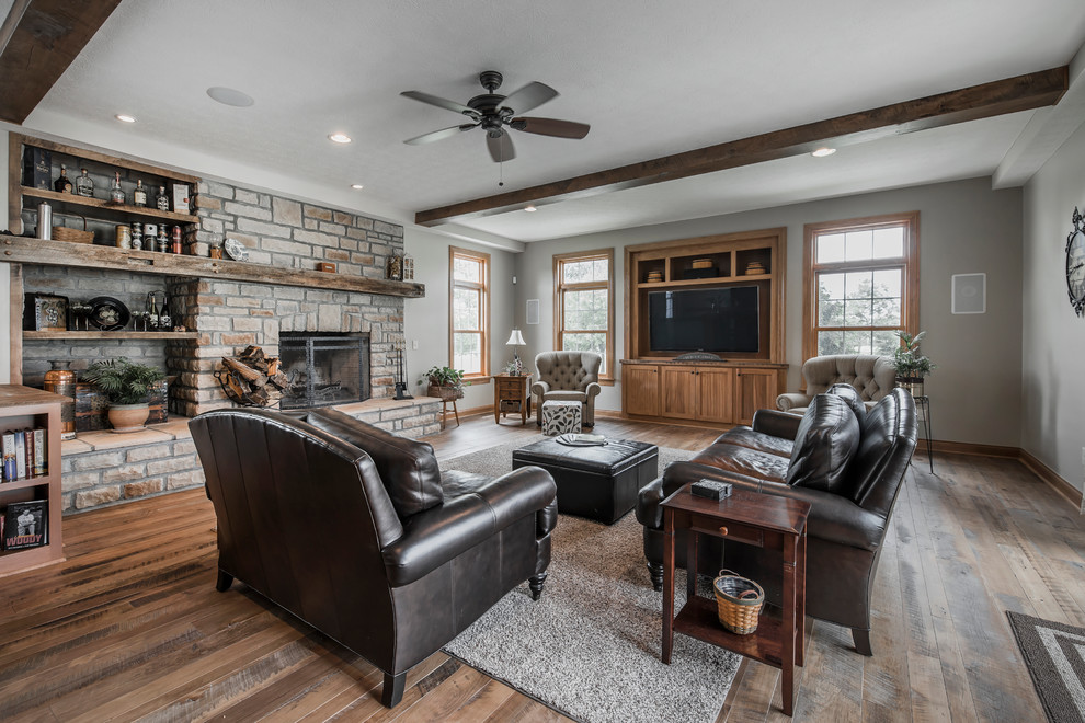 Inspiration for a large rustic enclosed games room in Columbus with grey walls, medium hardwood flooring, a stone fireplace surround, a built-in media unit, a standard fireplace and multi-coloured floors.