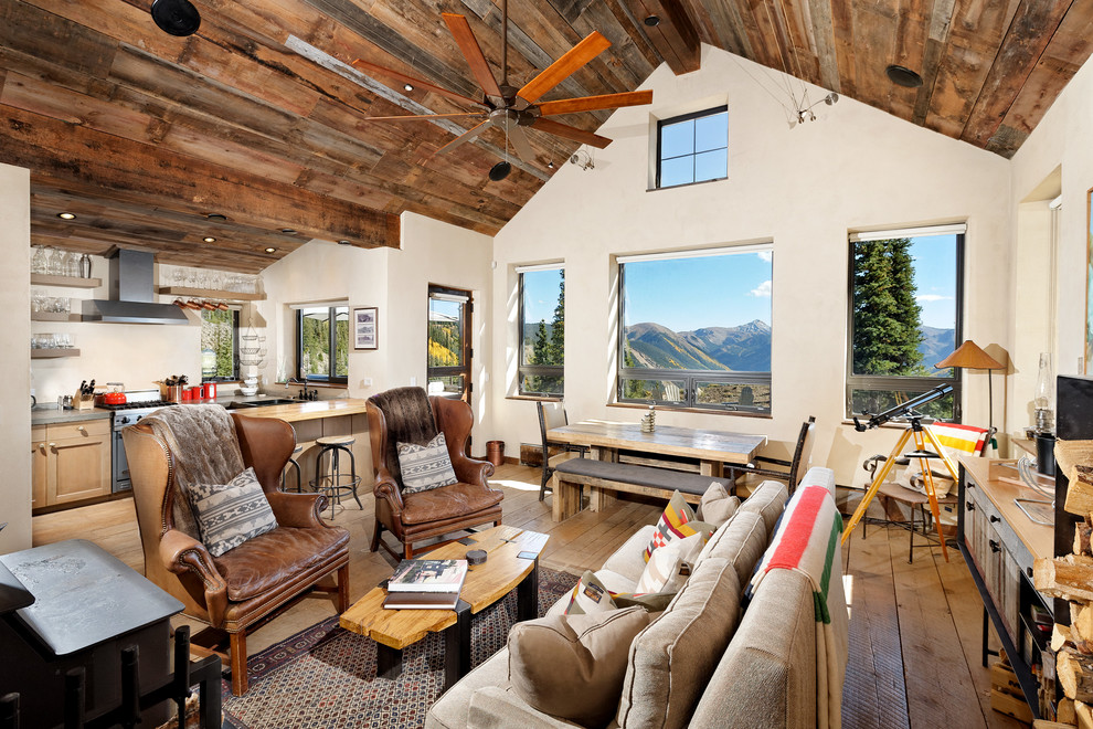Imagen de sala de estar abierta rural con paredes beige y suelo de madera clara