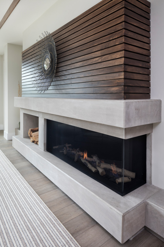 This is an example of a large modern open plan games room in Minneapolis with white walls, medium hardwood flooring, a ribbon fireplace, a wall mounted tv, brown floors and a concrete fireplace surround.