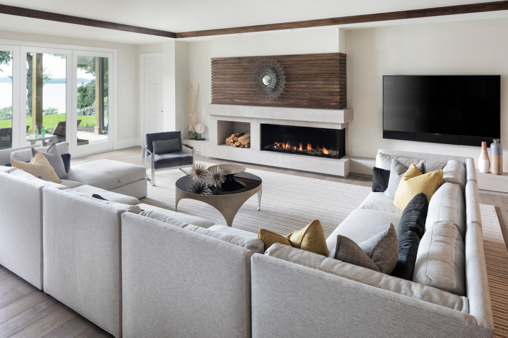 Diseño de sala de estar abierta contemporánea grande con paredes blancas, suelo de madera en tonos medios, chimenea lineal, televisor colgado en la pared y suelo marrón