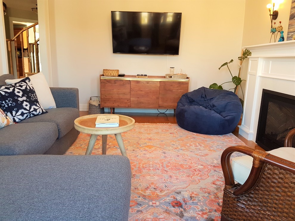 Mittelgroßes, Abgetrenntes Shabby-Look Wohnzimmer mit weißer Wandfarbe, braunem Holzboden, Kamin, Kaminumrandung aus Holz, TV-Wand und gelbem Boden in Toronto