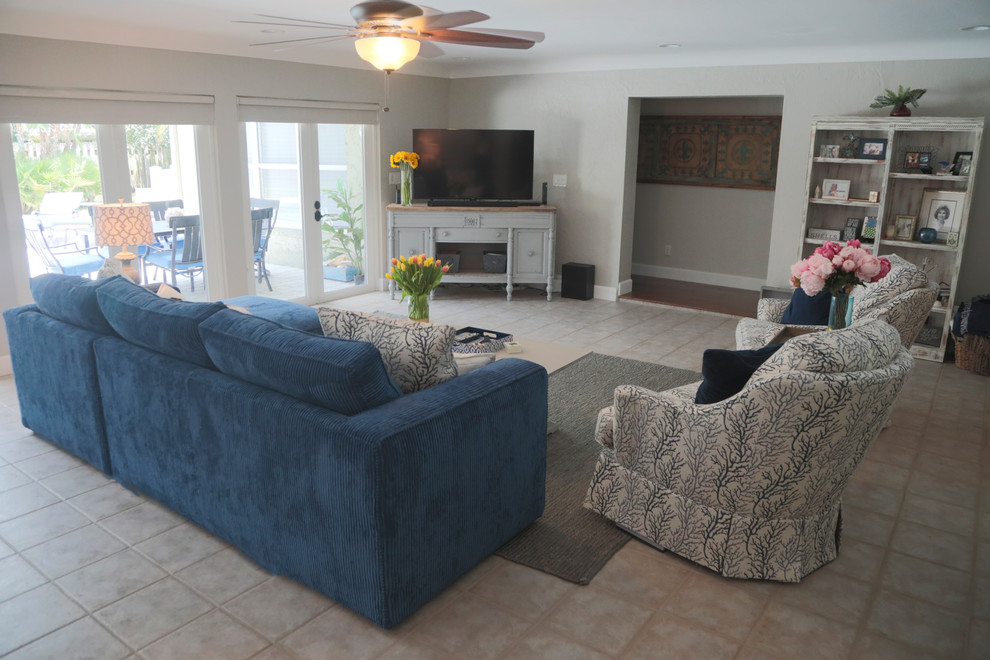 Foto de sala de estar cerrada costera grande sin chimenea con paredes grises, suelo de baldosas de cerámica, televisor en una esquina y suelo beige