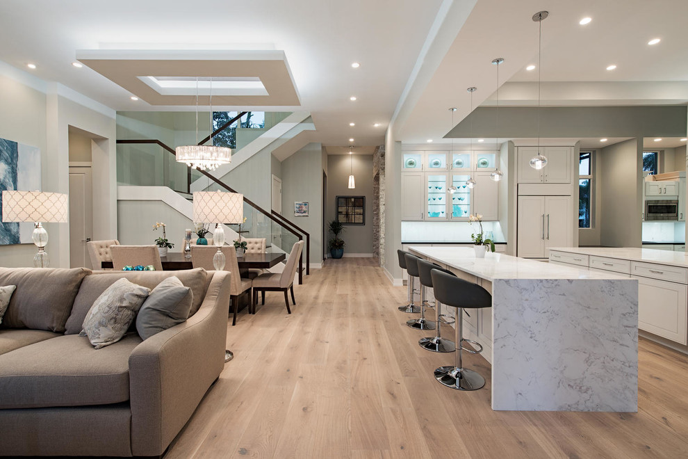 Modelo de sala de estar abierta clásica renovada con paredes blancas, suelo de madera en tonos medios y pared multimedia