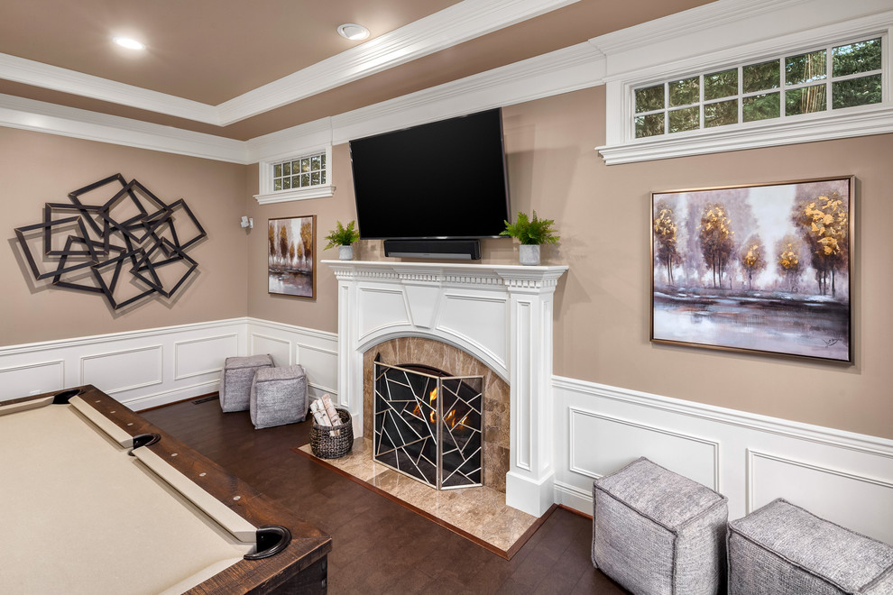 シアトルにある高級な中くらいなトラディショナルスタイルのおしゃれな独立型ファミリールーム (ゲームルーム、ベージュの壁、濃色無垢フローリング、標準型暖炉、木材の暖炉まわり、壁掛け型テレビ、茶色い床) の写真