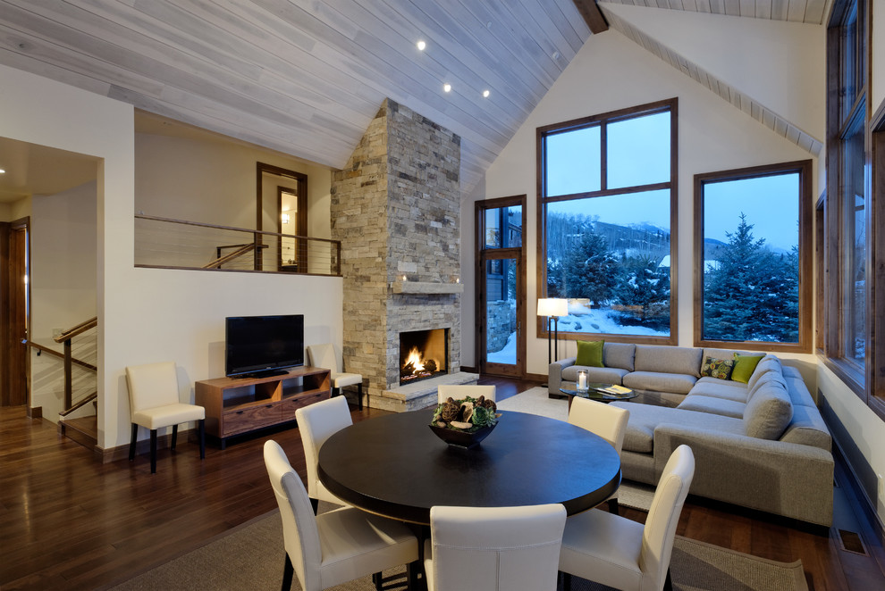 Cette image montre un salon design ouvert avec un mur beige, parquet foncé, une cheminée standard, un manteau de cheminée en pierre et un téléviseur indépendant.