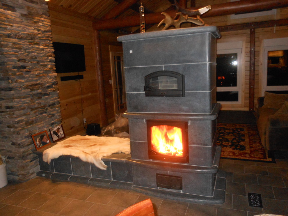 他の地域にあるラスティックスタイルのおしゃれなファミリールーム (セラミックタイルの床、石材の暖炉まわり) の写真