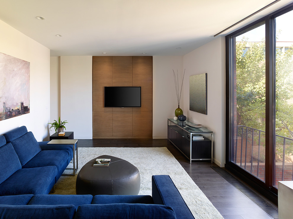 Réalisation d'une salle de séjour design avec un mur blanc, parquet foncé, un téléviseur fixé au mur et un sol marron.