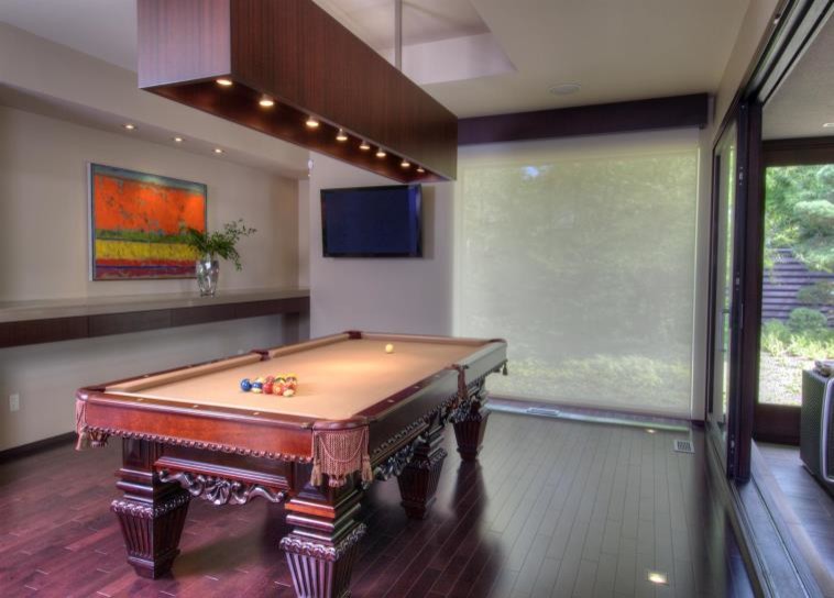 Mittelgroßer, Abgetrennter Moderner Hobbyraum mit weißer Wandfarbe, braunem Holzboden und TV-Wand in Charleston