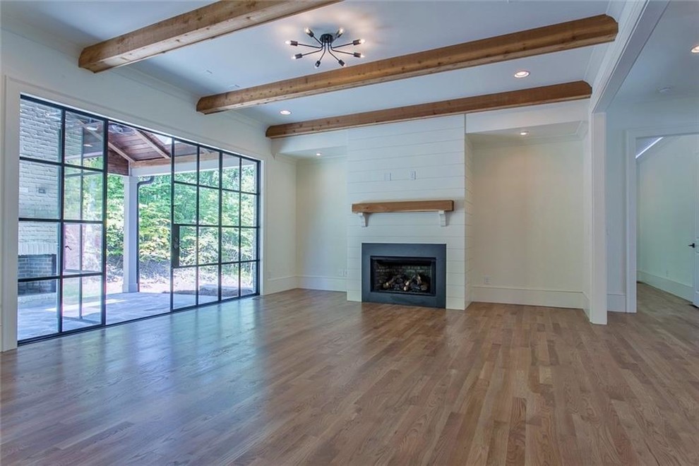 Inspiration for a large transitional open concept light wood floor and gray floor family room remodel in Atlanta with white walls, a standard fireplace, a stone fireplace and a wall-mounted tv