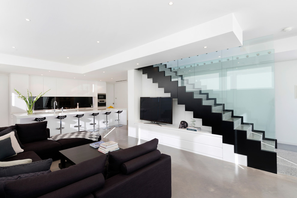 Aménagement d'une salle de séjour contemporaine ouverte avec sol en béton ciré, un téléviseur indépendant et canapé noir.